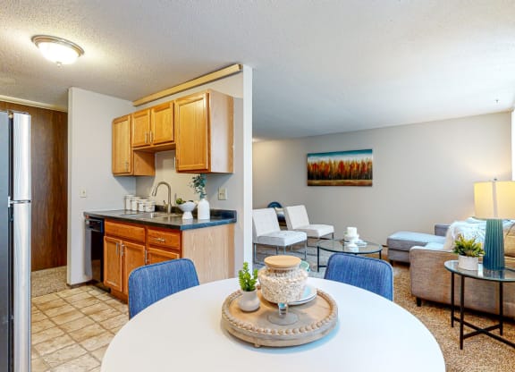 a living room with a table and chairs and a kitchen in the background