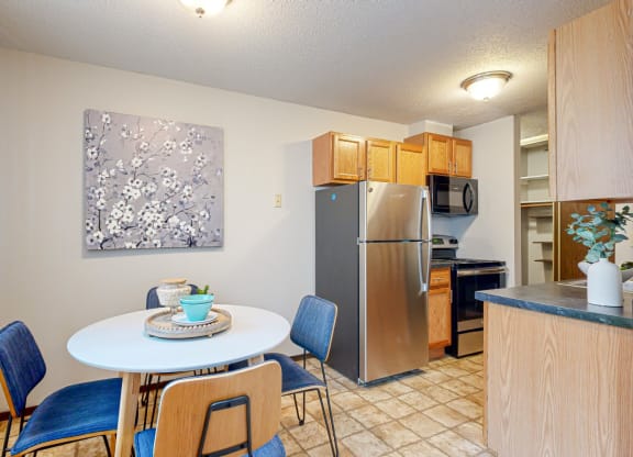 a dining area with a table and chairs and a kitchen in the background
