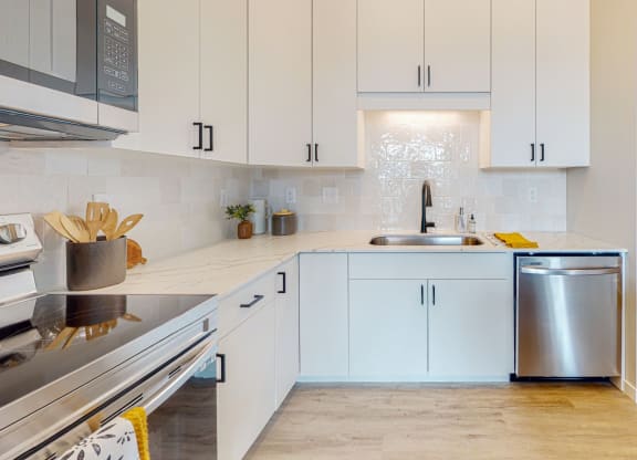 a kitchen with white cabinets and a stainless steel dishwasher
