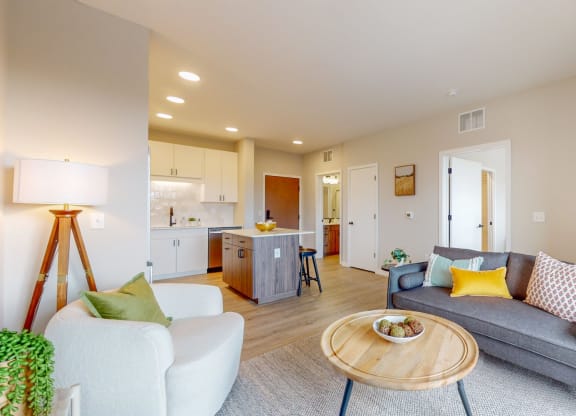 a living room with a couch coffee table and a kitchen in the background