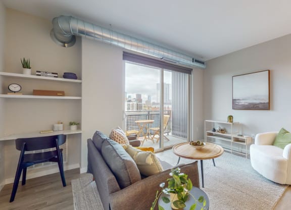 a living area with a couch chair coffee table and sliding glass door to a balcony