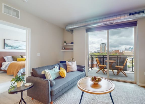 a living area with a couch coffee table and sliding glass door to a balcony