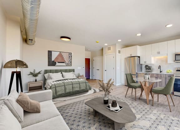 a living room with a bed and a kitchen in the background