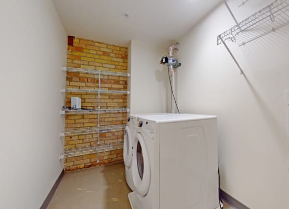 a washer and dryer in a laundry room with a brick wall