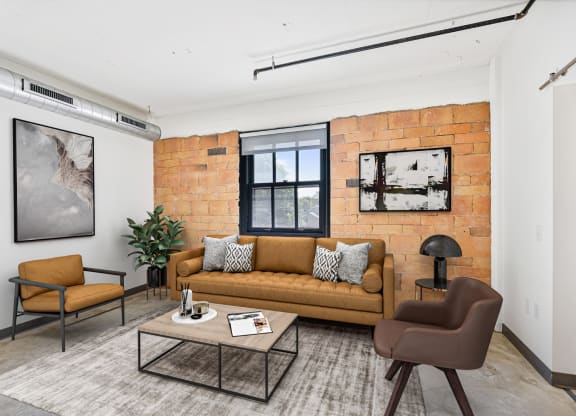a living room with a couch and a coffee table and a brick wall