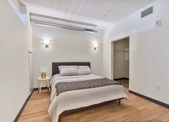 A bedroom with a bed, nightstand, and a lamp.