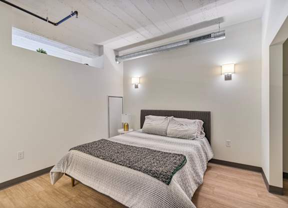 A bedroom with a bed, pillows, and a grey blanket.