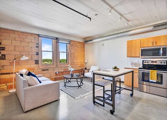 A living room with a couch, a table, and a brick wall.