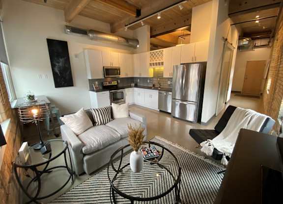 A modern living room with a black and white striped rug and a glass coffee table.