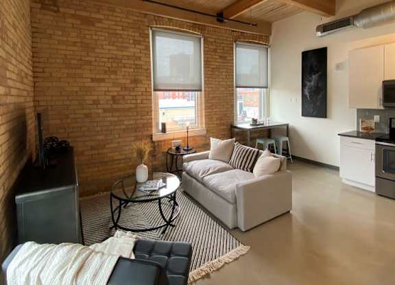 A living room with a couch, chair, and a table with a blanket on it.