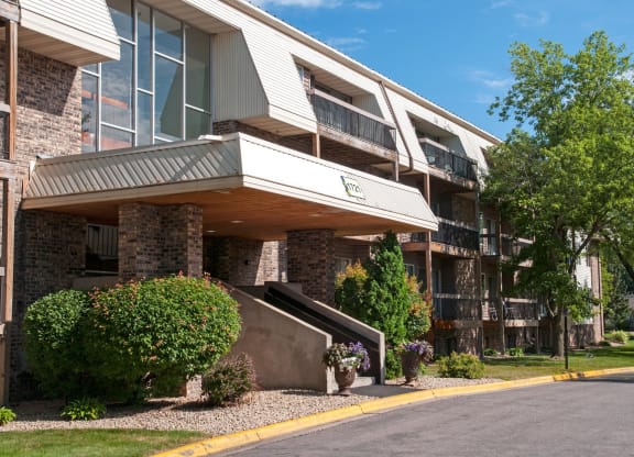 an apartment building with a road and trees in front of it