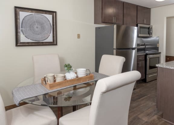a dining room with a table and chairs and a kitchen with stainless steel appliances