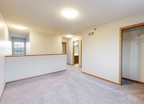 A spacious room with a carpeted floor and a sliding glass door.