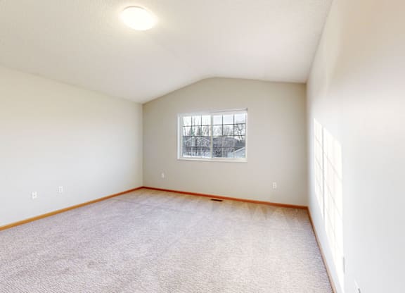 A room with a window and carpeted floor.