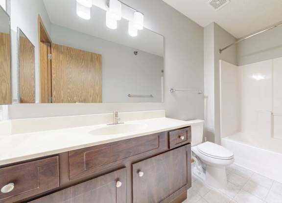 A bathroom with a white countertop and a white toilet.