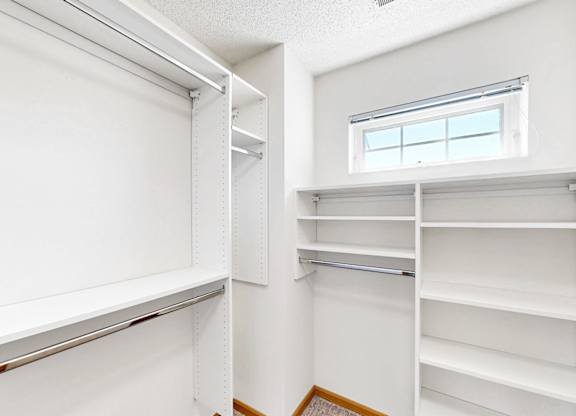 A white walk-in closet with shelves and a window.