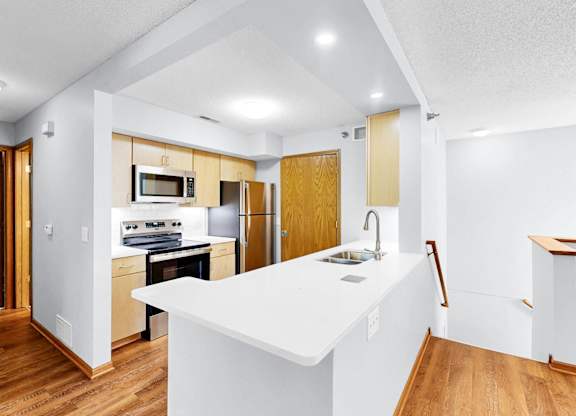 A kitchen with a white counter top and wooden floors.