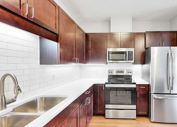 A kitchen with a refrigerator, sink, and oven.