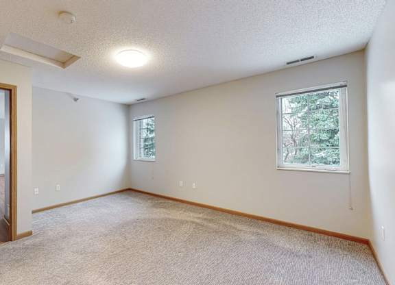 A room with a door, a window, and a carpeted floor.