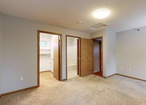A room with a carpeted floor and three doors.