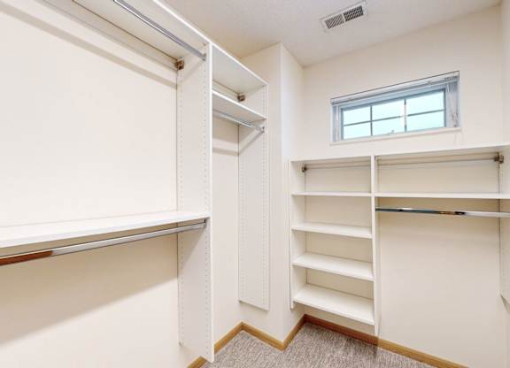 A white closet with shelves and a window.