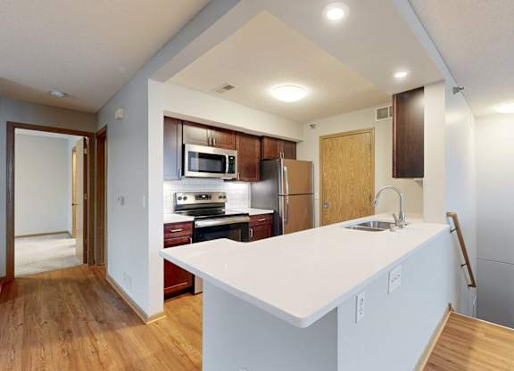 A kitchen with a white counter top and wooden floors.
