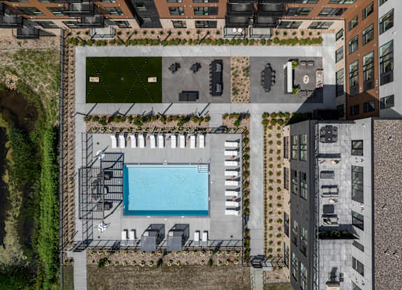 An aerial view of a pool surrounded by lounge chairs and buildings.