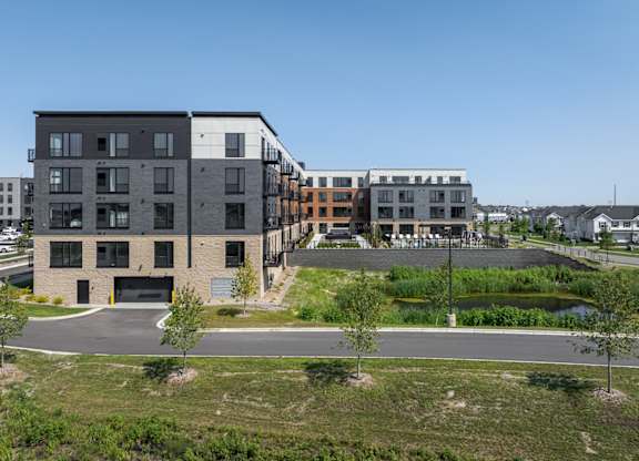 A modern building complex with a parking lot in front.
