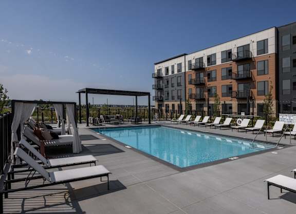 A pool area with sun loungers and a building in the background.