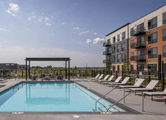 A swimming pool surrounded by lounge chairs and umbrellas.