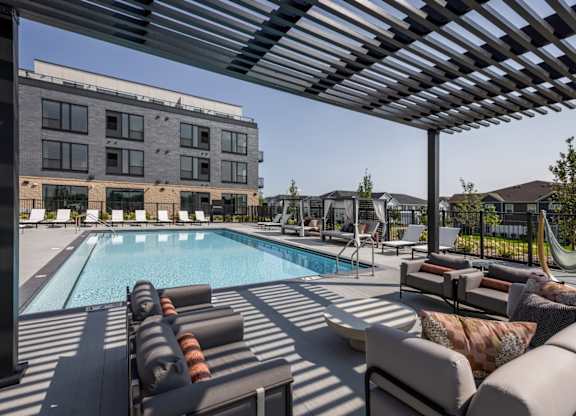 A pool area with sun loungers and a building in the background.