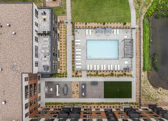 A bird's eye view of a building with a pool and parking lot.