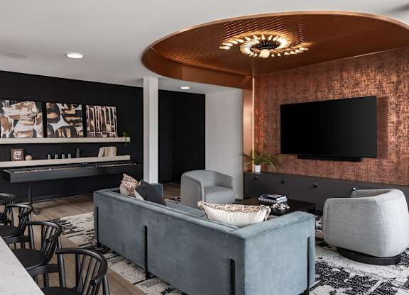 A modern living room with a grey sofa and a wooden ceiling light.