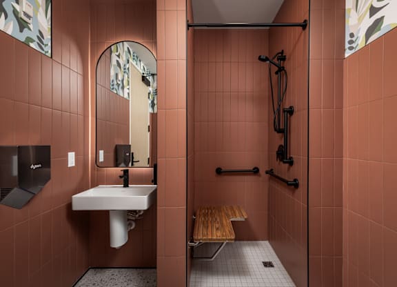 A bathroom with a sink, mirror, and shower.
