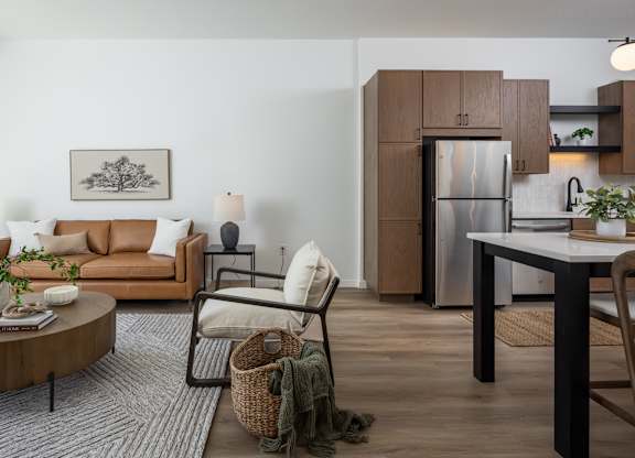A modern living room with a brown sofa, a coffee table, and a dining table.