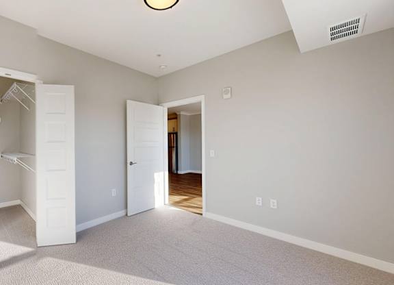 A white closet with a white door is open in a room with a carpeted floor.