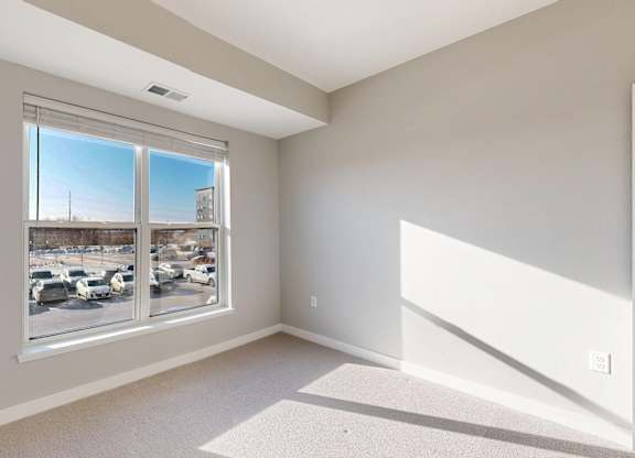 A room with a large window overlooking a parking lot.