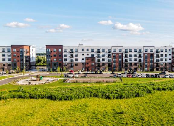 A large grassy field in front of a row of apartment buildings. at The Edison at Maple Grove, Minnesota, 55311