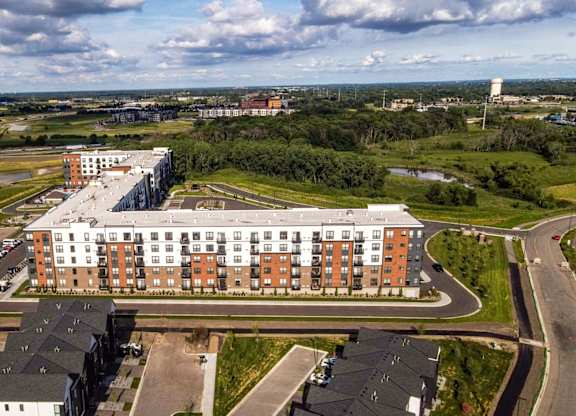 A large building with a parking lot in front of it. at The Edison at Maple Grove, Maple Grove