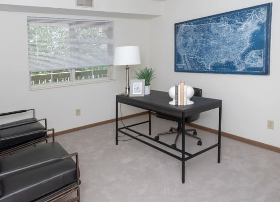 a room with a desk and chair and a large blue map on the wall