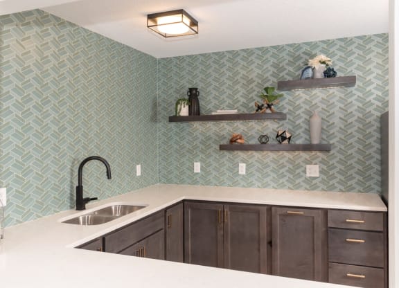 a kitchen with green tile and white countertops