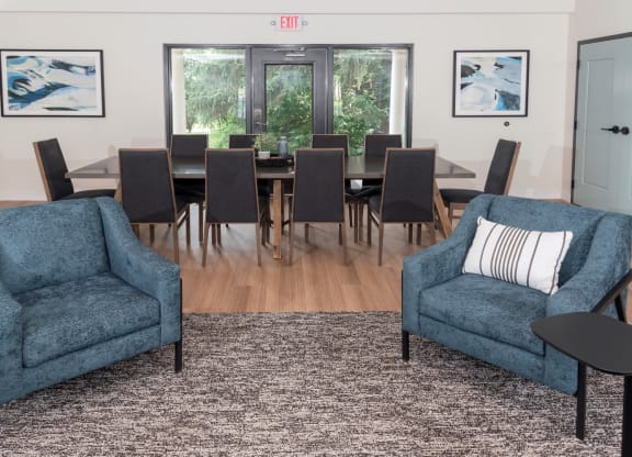 a living room with two blue chairs and a large dining table