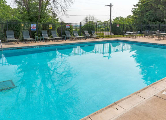 a swimming pool with chaise lounge chairs and trees in the background