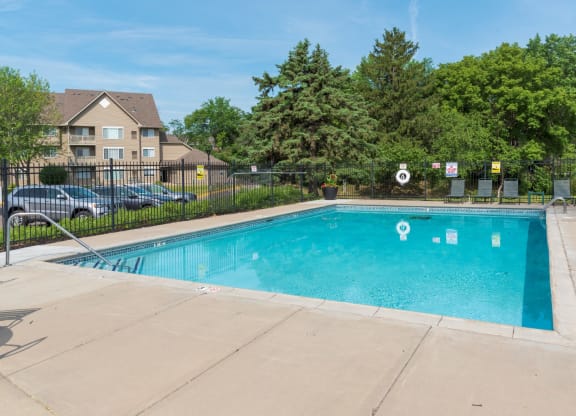 a swimming pool with a fence and trees in the background