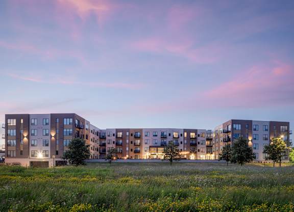 A modern apartment complex is lit up at dusk.