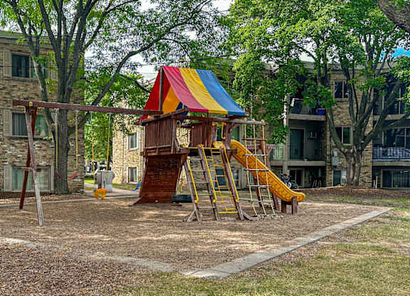 A playground with a yellow slide and a red, white, and blue canopy.