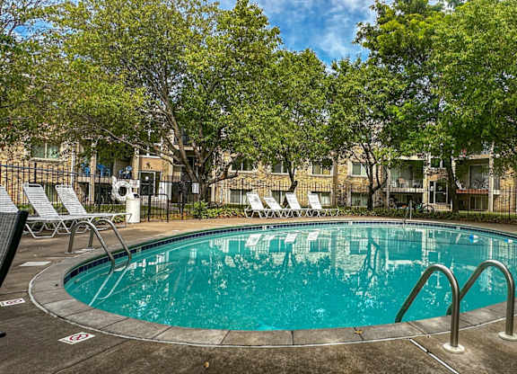 A round swimming pool surrounded by trees and chairs.