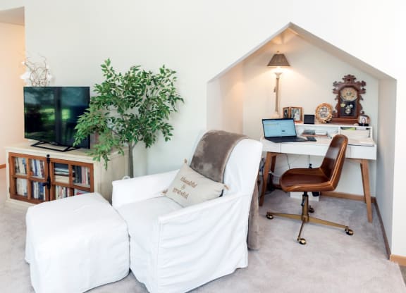 a living room with a white couch and a desk with a computer