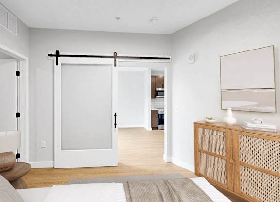 A bedroom with a bed, nightstand, and sliding door.