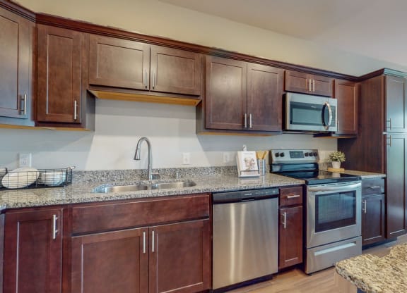 a kitchen with dark wood cabinets and granite countertops at Lake Jonathan Flats, Chaska, MN